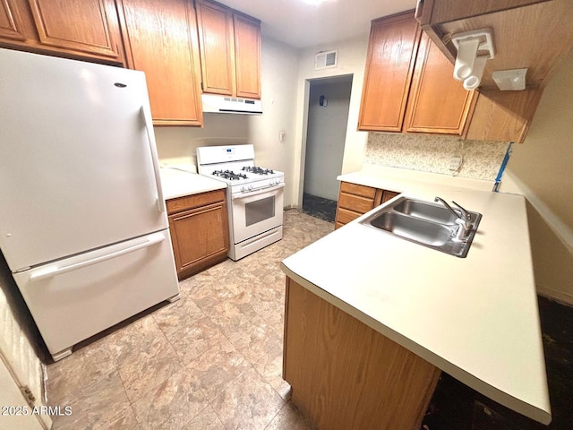 kitchen featuring white appliances, light countertops, a sink, and under cabinet range hood