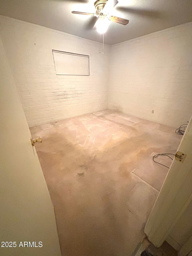 interior space featuring a ceiling fan, carpet flooring, and brick wall