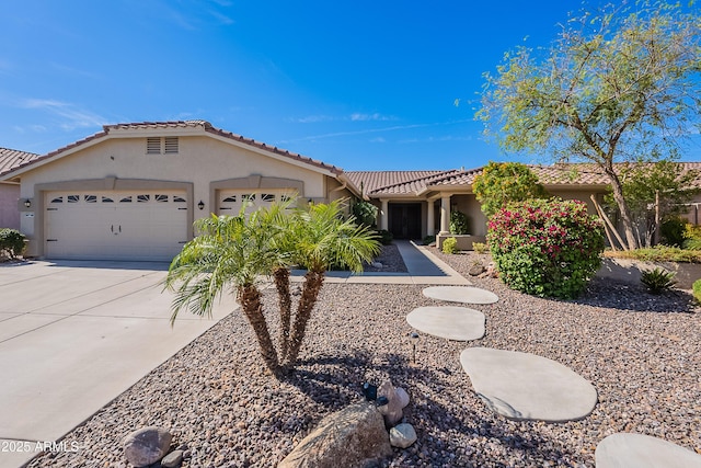 mediterranean / spanish-style house with concrete driveway, a garage, stucco siding, and a tiled roof