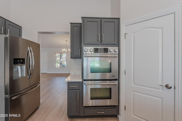 kitchen featuring gray cabinetry, light countertops, appliances with stainless steel finishes, and light wood-style flooring