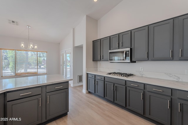 kitchen featuring light wood finished floors, an inviting chandelier, high vaulted ceiling, visible vents, and appliances with stainless steel finishes