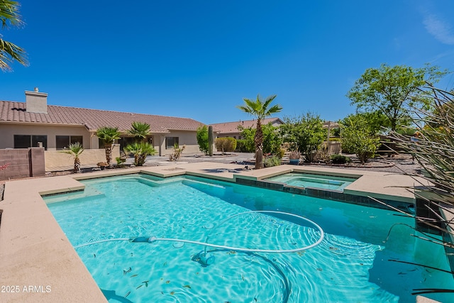 view of swimming pool with fence and a pool with connected hot tub