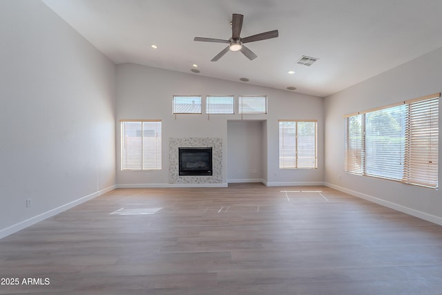 unfurnished living room with a glass covered fireplace, a ceiling fan, visible vents, light wood-style flooring, and lofted ceiling