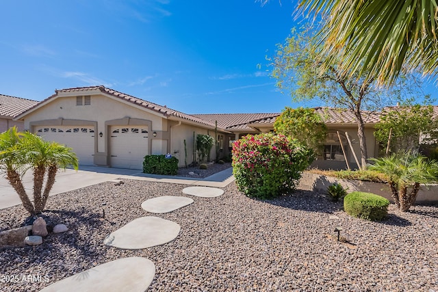 view of front facade featuring a tile roof, concrete driveway, an attached garage, and stucco siding
