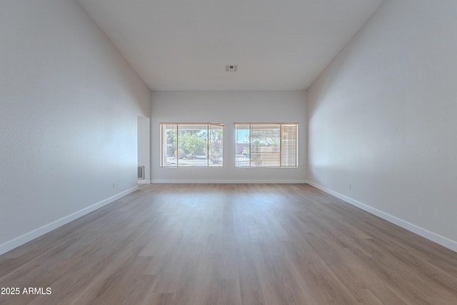 unfurnished room featuring visible vents, wood finished floors, and baseboards