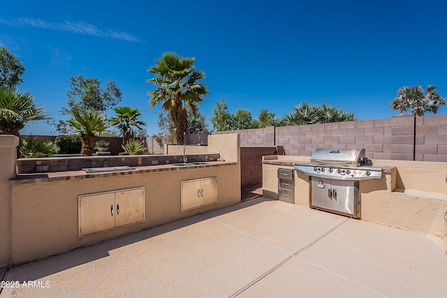 view of patio with fence, area for grilling, and an outdoor kitchen