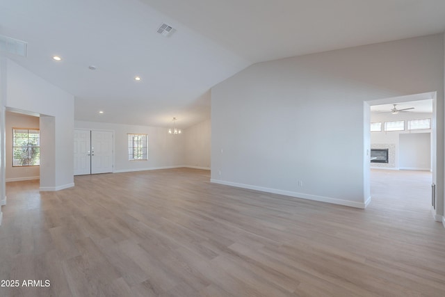 unfurnished living room with a glass covered fireplace, a healthy amount of sunlight, visible vents, and baseboards