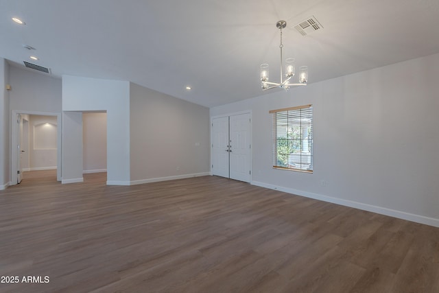 unfurnished living room featuring visible vents, a chandelier, and baseboards