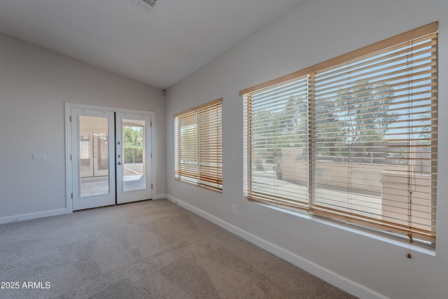 carpeted empty room featuring french doors, vaulted ceiling, and baseboards