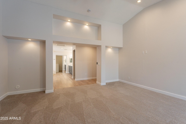 spare room with baseboards, high vaulted ceiling, light carpet, and recessed lighting