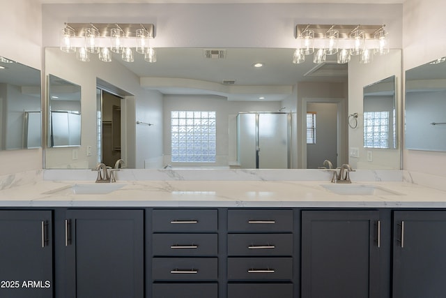 bathroom with visible vents, a shower stall, double vanity, and a sink