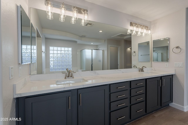 full bath with a stall shower, wood finished floors, double vanity, and a sink