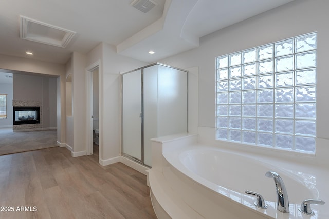 bathroom featuring a shower stall, a bath, visible vents, wood finished floors, and plenty of natural light