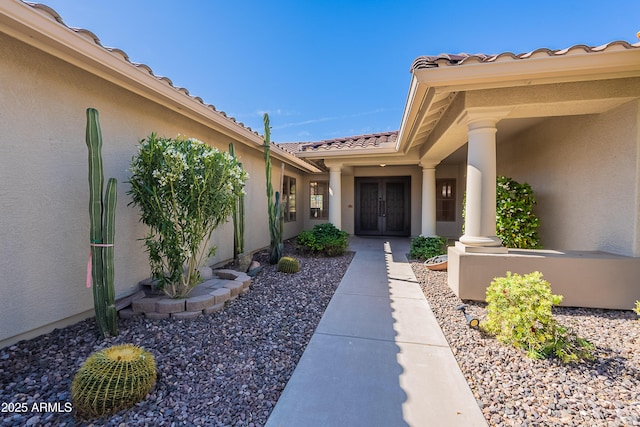 entrance to property with stucco siding, french doors, and a tile roof