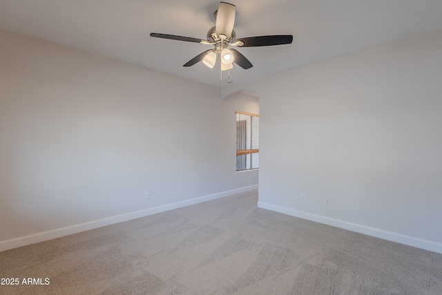 spare room featuring a ceiling fan, carpet flooring, arched walkways, and baseboards