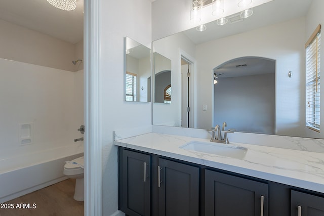 full bathroom featuring vanity, ceiling fan, toilet, visible vents, and  shower combination