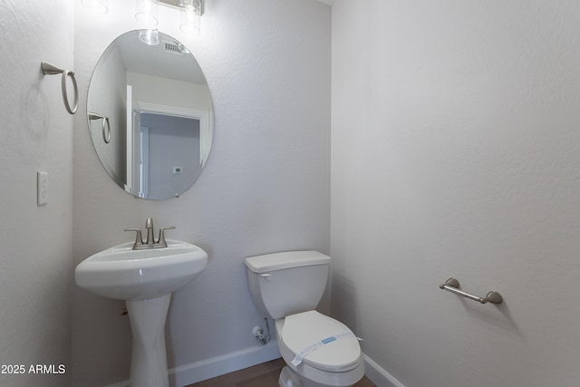 bathroom featuring a sink, wood finished floors, toilet, and baseboards