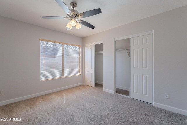 unfurnished bedroom with two closets, baseboards, and light carpet