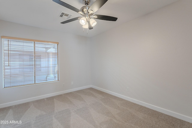 unfurnished room featuring a ceiling fan, visible vents, light colored carpet, and baseboards