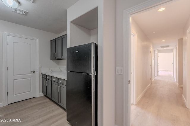 kitchen featuring visible vents, gray cabinets, freestanding refrigerator, and light wood-style floors