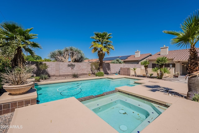 view of swimming pool featuring a pool with connected hot tub, a patio, and a fenced backyard