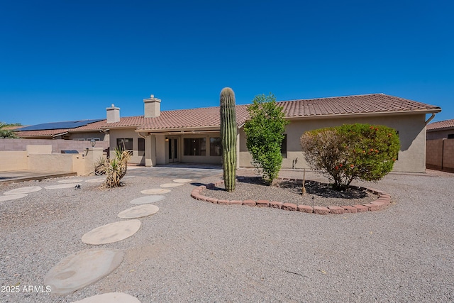 rear view of property with a patio area, a tiled roof, a chimney, stucco siding, and fence