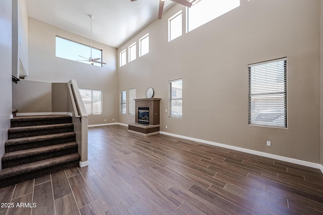 125 N 22nd Pl Unit 14, Mesa, AZ 85213 - unfurnished living room featuring a ceiling fan, stairway, dark wood-style floors, a towering ceiling, and baseboards