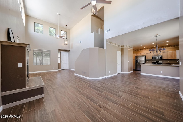 125 N 22nd Pl Unit 14, Mesa, AZ 85213 - unfurnished living room featuring a high ceiling, ceiling fan, a chandelier, dark wood-style floors, and baseboards