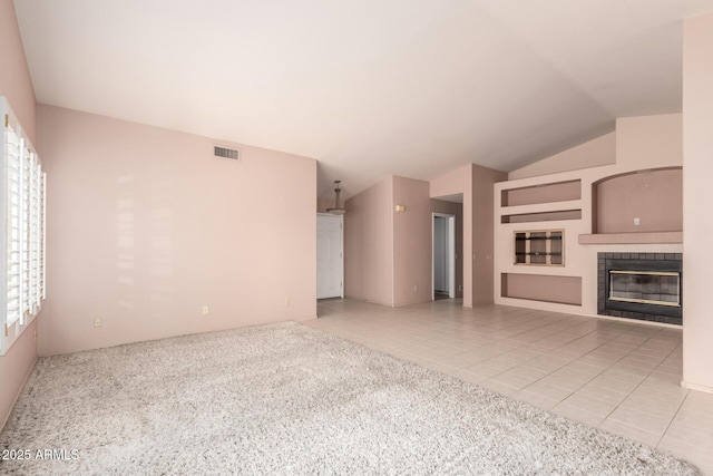 24907 S Lakestar Dr, Sun Lakes, AZ 85248 - unfurnished living room with a tile fireplace, healthy amount of natural light, light tile patterned floors, light colored carpet, and lofted ceiling