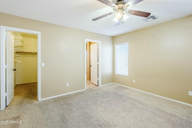 unfurnished bedroom with ceiling fan, light carpet, a closet, and a spacious closet