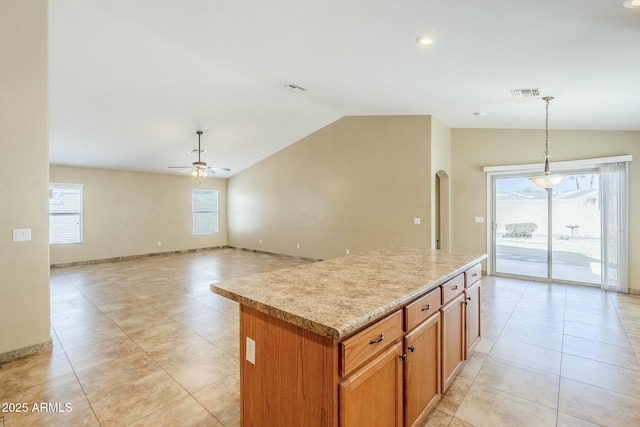 kitchen featuring vaulted ceiling, light tile patterned floors, a center island, decorative light fixtures, and ceiling fan