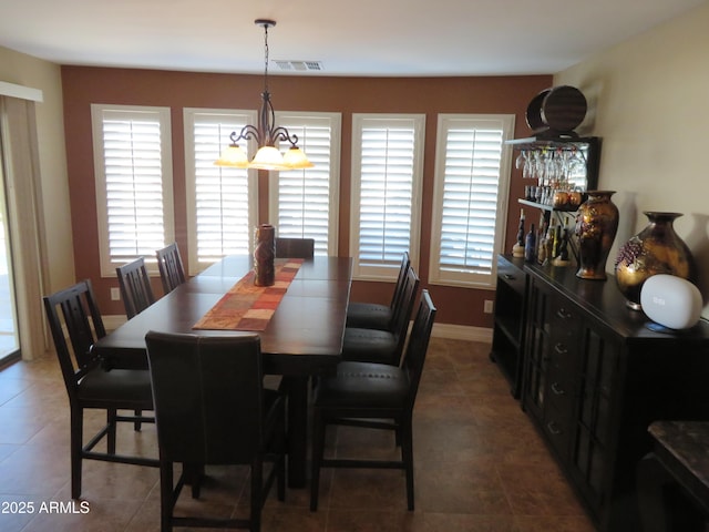 dining room featuring dark tile patterned floors and a chandelier