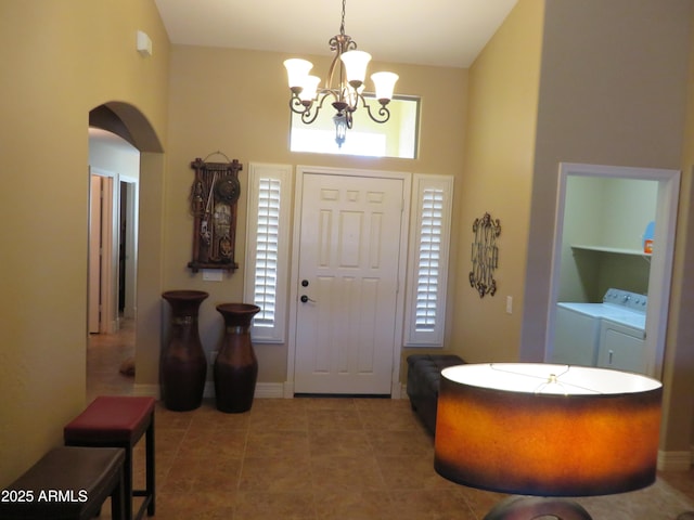 foyer entrance featuring independent washer and dryer, tile patterned floors, a notable chandelier, and a towering ceiling