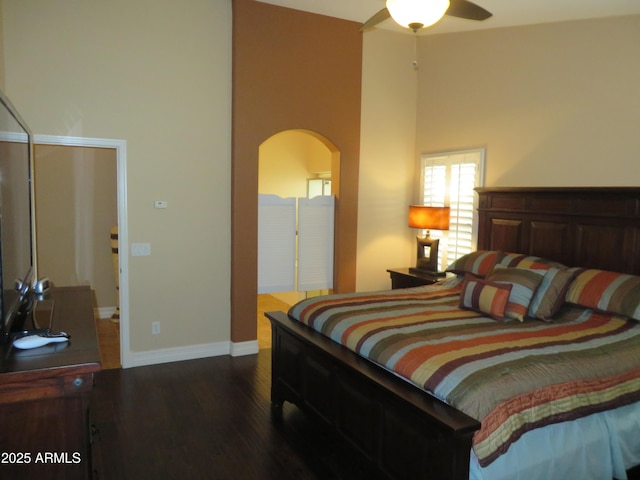 bedroom with a towering ceiling and dark hardwood / wood-style floors