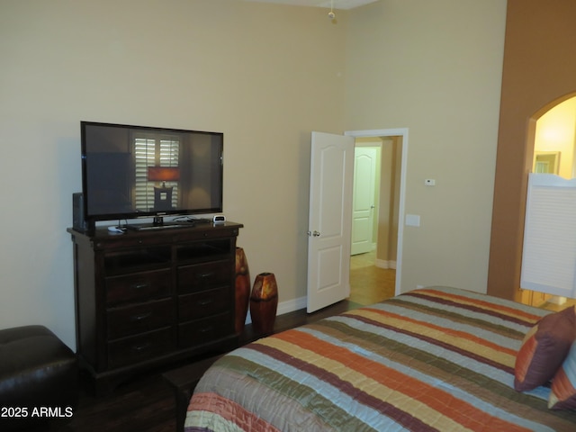 bedroom featuring a towering ceiling and hardwood / wood-style flooring