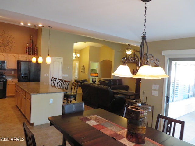 dining space featuring light tile patterned floors and ceiling fan with notable chandelier