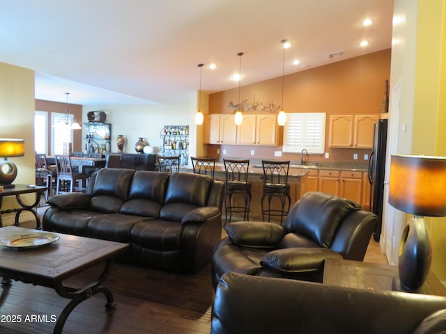 living room with an inviting chandelier, sink, hardwood / wood-style flooring, and high vaulted ceiling