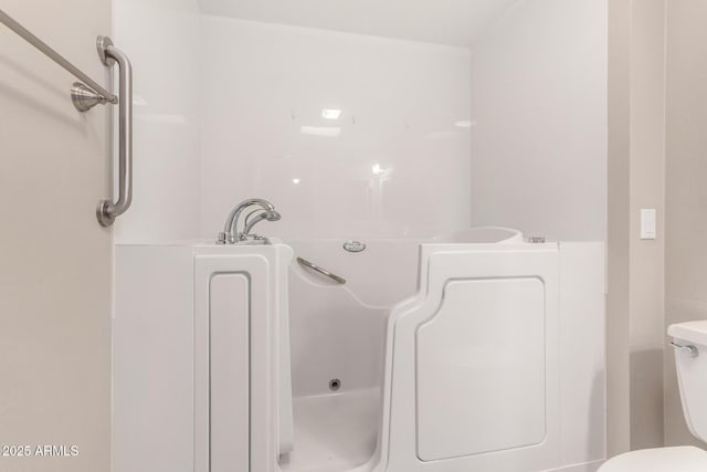 bathroom with toilet and a tub with jets