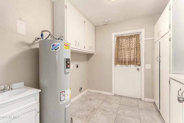 washroom featuring a sink, electric water heater, cabinet space, light tile patterned floors, and hookup for an electric dryer