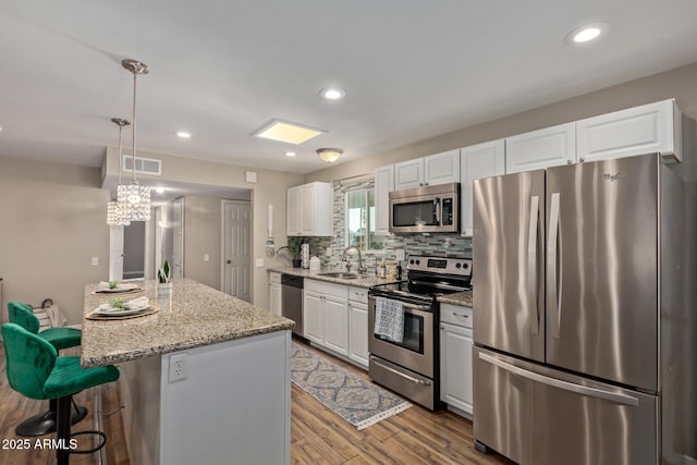 kitchen with visible vents, a kitchen breakfast bar, white cabinets, stainless steel appliances, and a sink