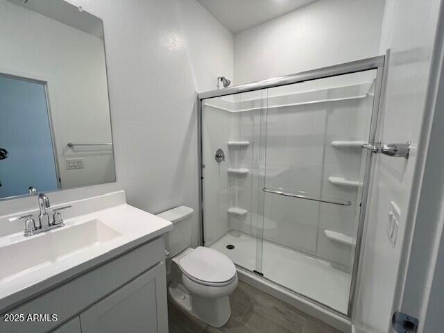 bathroom featuring vanity, toilet, and an enclosed shower