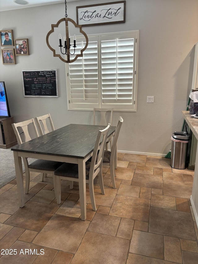 dining space with a chandelier, stone finish floor, and baseboards