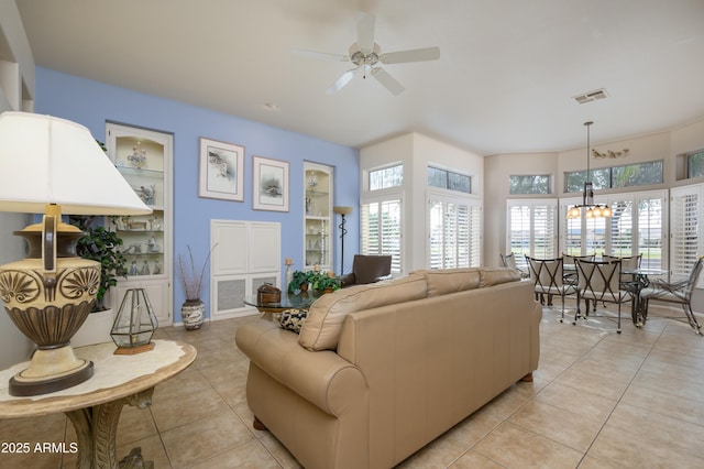 tiled living room with built in shelves and ceiling fan with notable chandelier