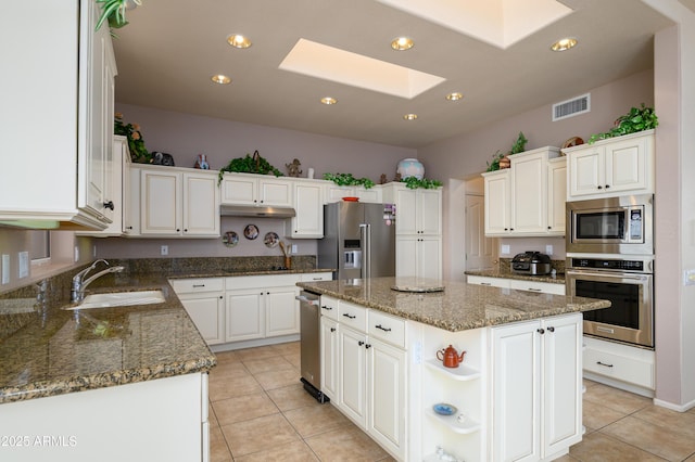 kitchen featuring a skylight, sink, white cabinets, a center island, and stainless steel appliances