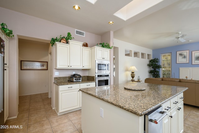 kitchen with light tile patterned flooring, white cabinetry, a center island, dark stone countertops, and appliances with stainless steel finishes