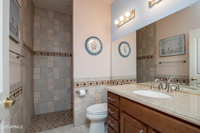 bathroom featuring a tile shower, tile walls, tile patterned flooring, vanity, and toilet