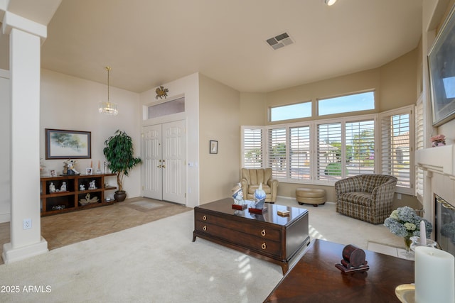 living room featuring a wealth of natural light, a fireplace, light colored carpet, and decorative columns