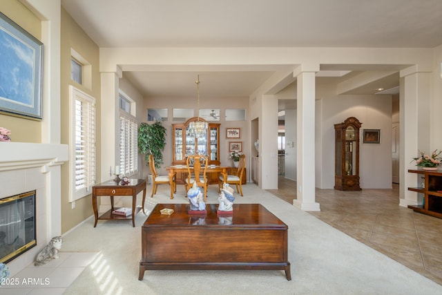 living room featuring light tile patterned floors, a fireplace, and decorative columns