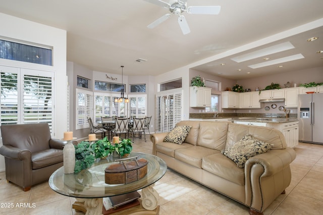 living room with sink, light tile patterned floors, and ceiling fan