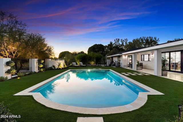 pool at dusk with a lawn and a patio area